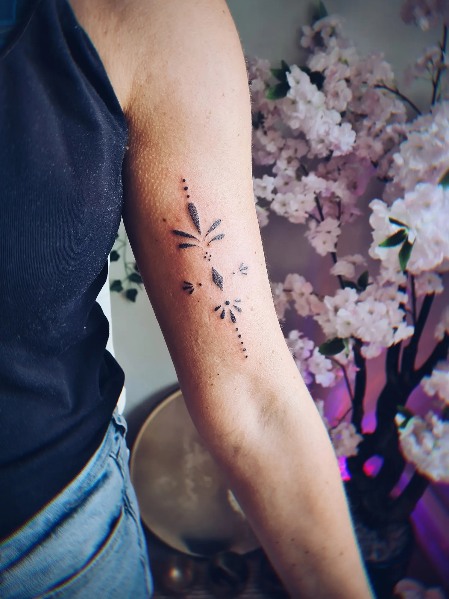 Fijne tattoo van blaadjes en stippen op de binnenarm