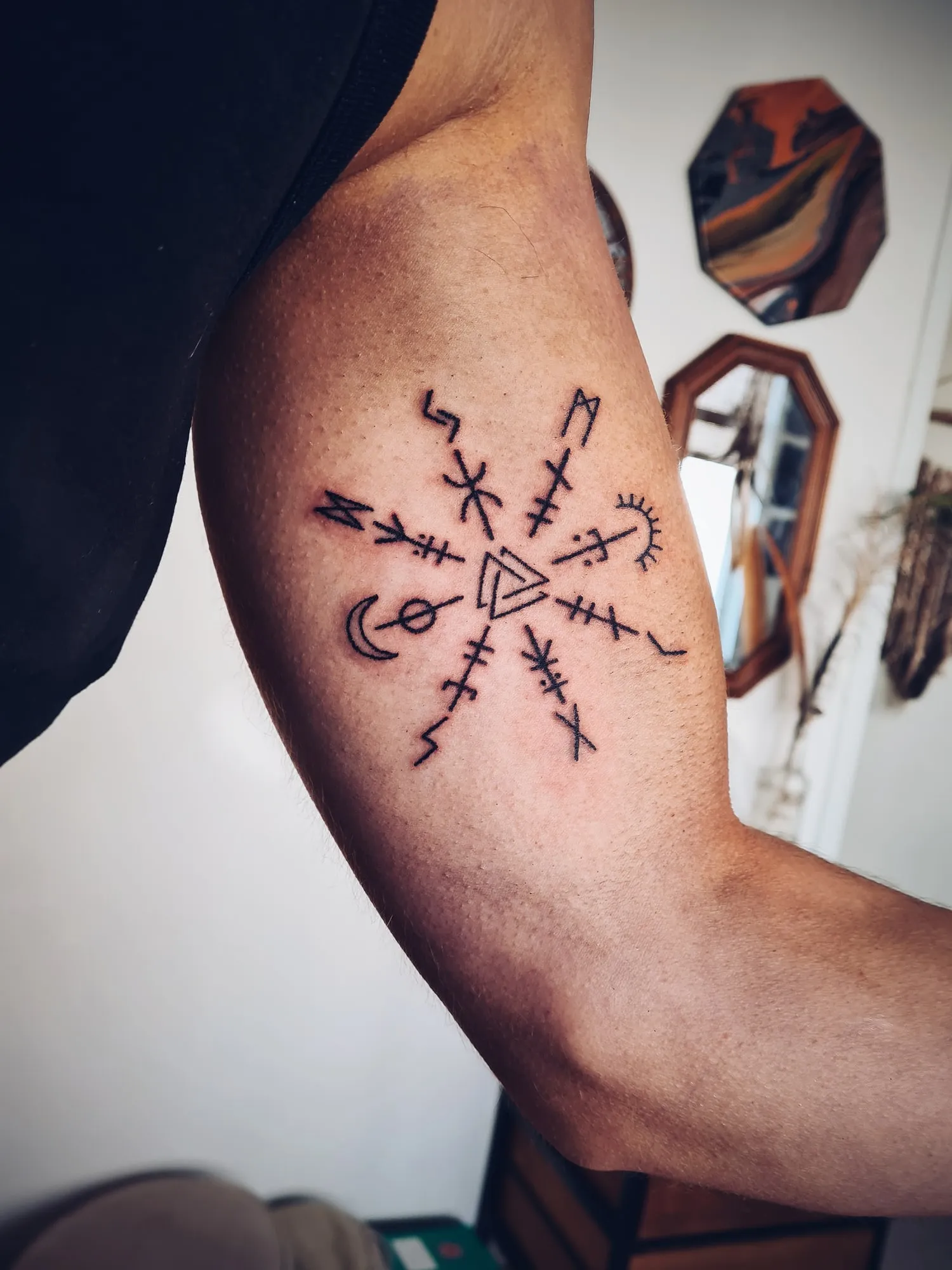 Tattoo van een kompas met symbolen op de bovenarm
