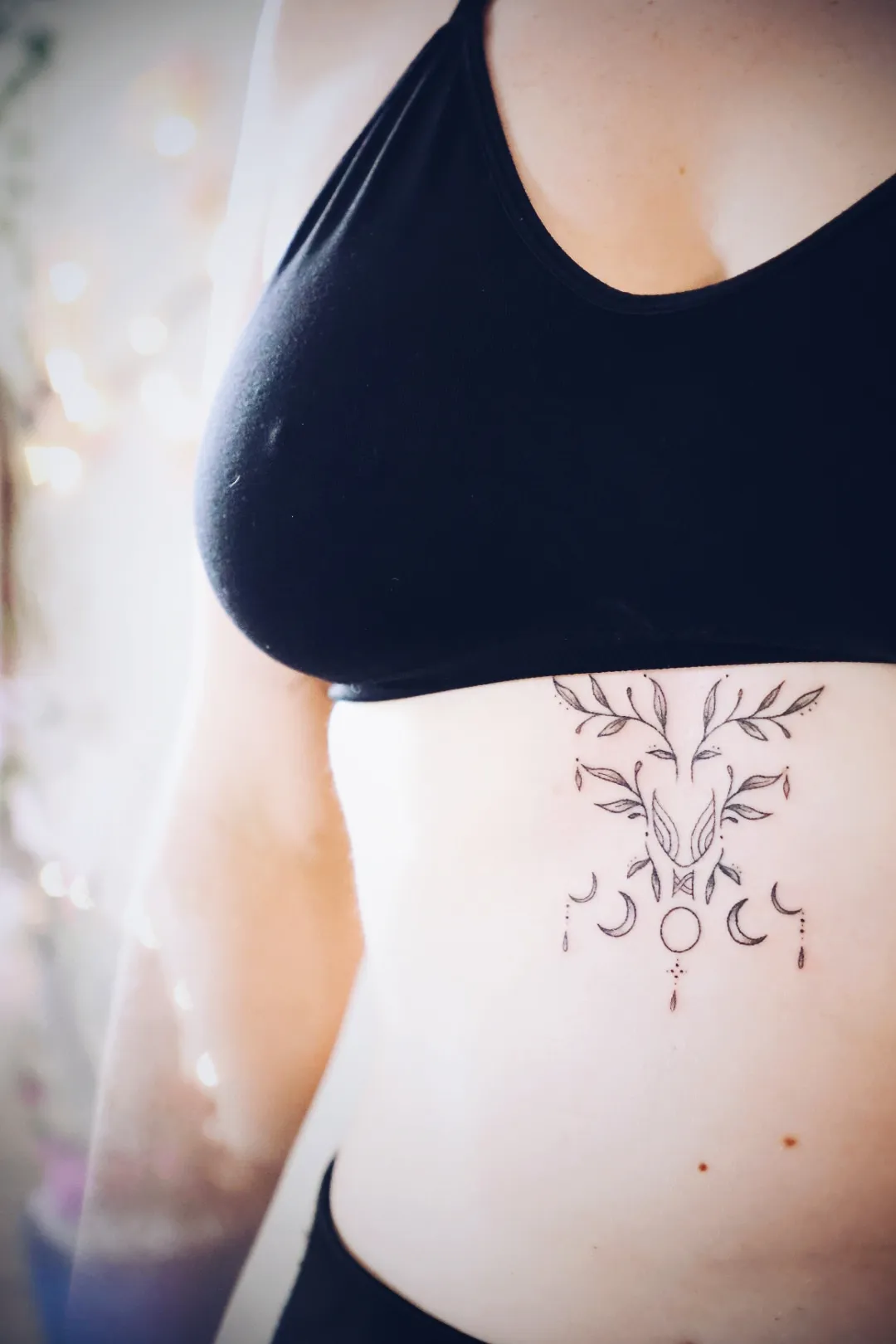 Botanische tattoo met maanfasen op de buik
