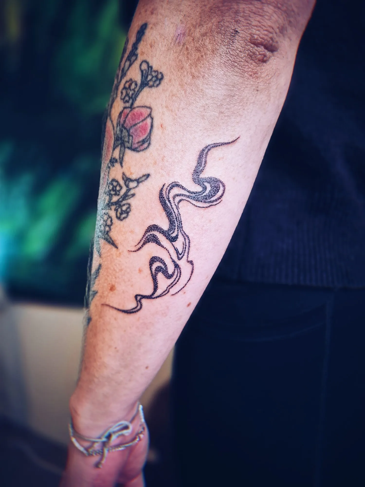Vloeiende lijntattoo op de onderarm