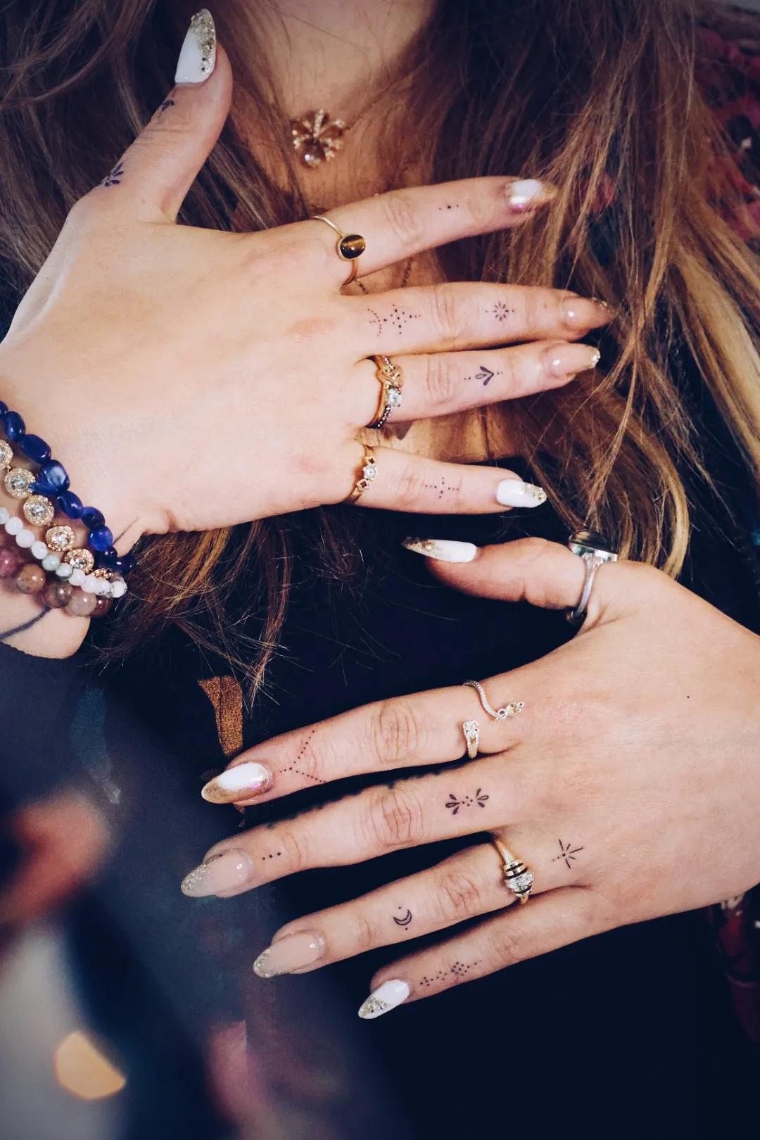 Handen met fijne handpoke-tattoos op de vingers