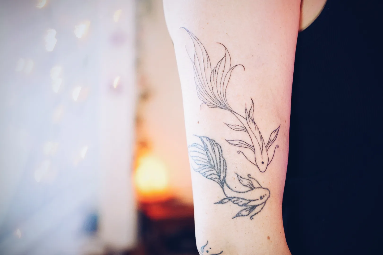 Fijne lijntattoo van twee koivissen op een onderarm
